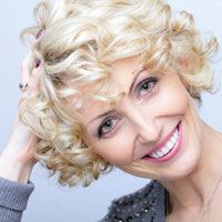 a blonde woman smiles after having a dental implants procedure