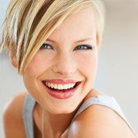 A young blonde woman smiles to show off her straight teeth